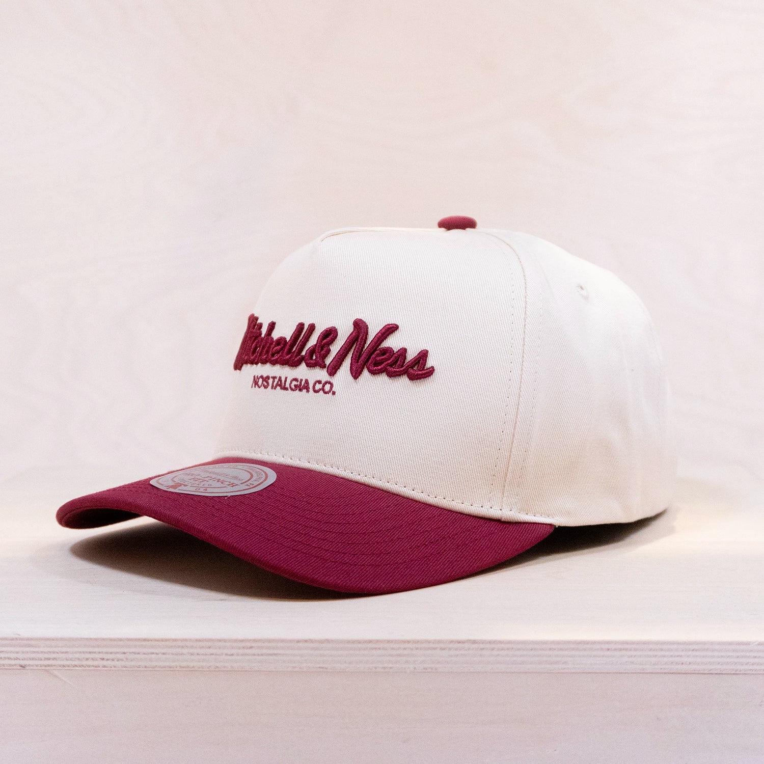 White and maroon cap with Mitchell & Ness logo on a light background