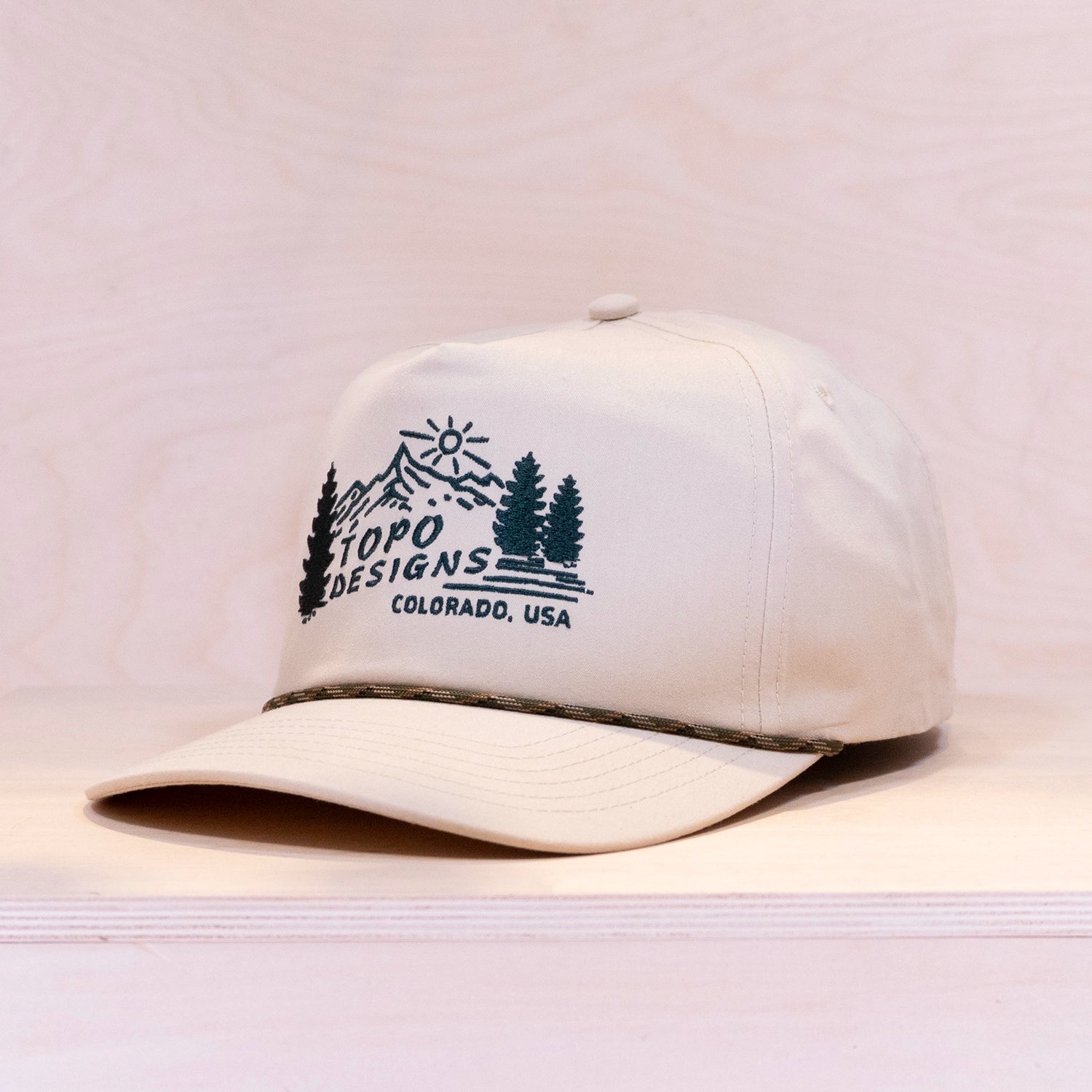 White cap with Topo Designs logo on a light gray background